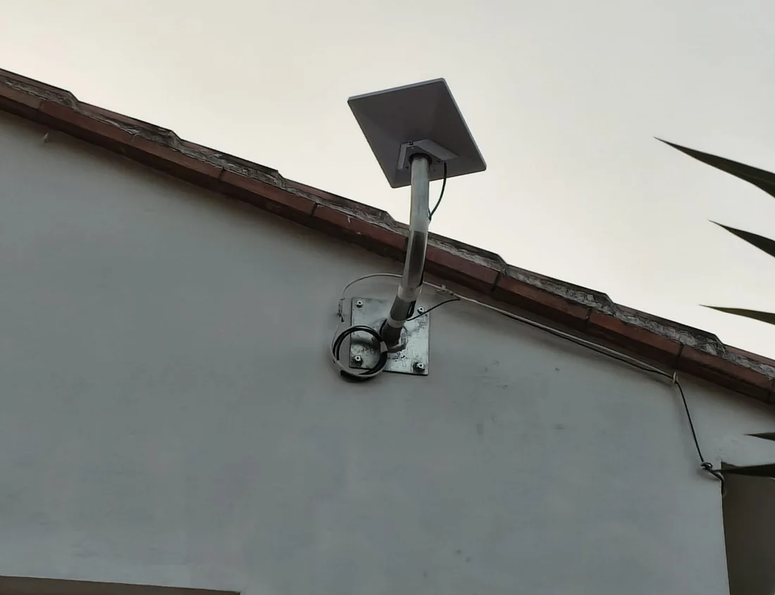 Antena de Starlink anclada con soporte de pared por encima del alero, con el cable haciendo su curva de goteo antes de entrar