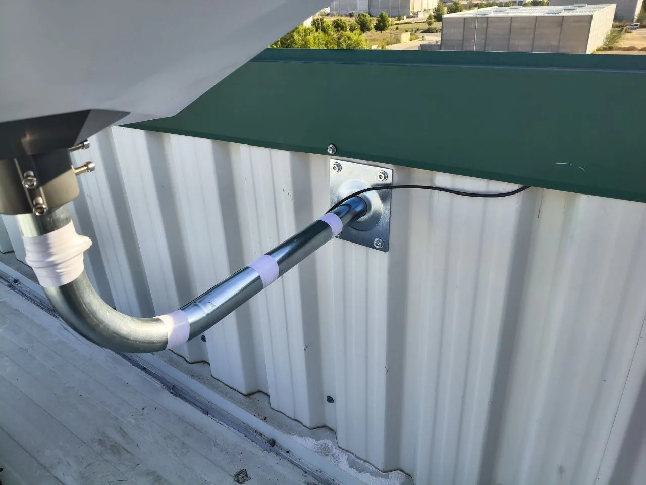 Detalle del mástil de la instalación de Cheste: tubo galvanizado en codo, placa con cuatro tornillos a la chapa de la nave y cinta blanca en las uniones